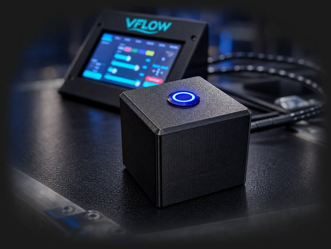 The VBOX button box, a compact black box with a glowing blue button, in front of a VFLOW touchscreen controller
